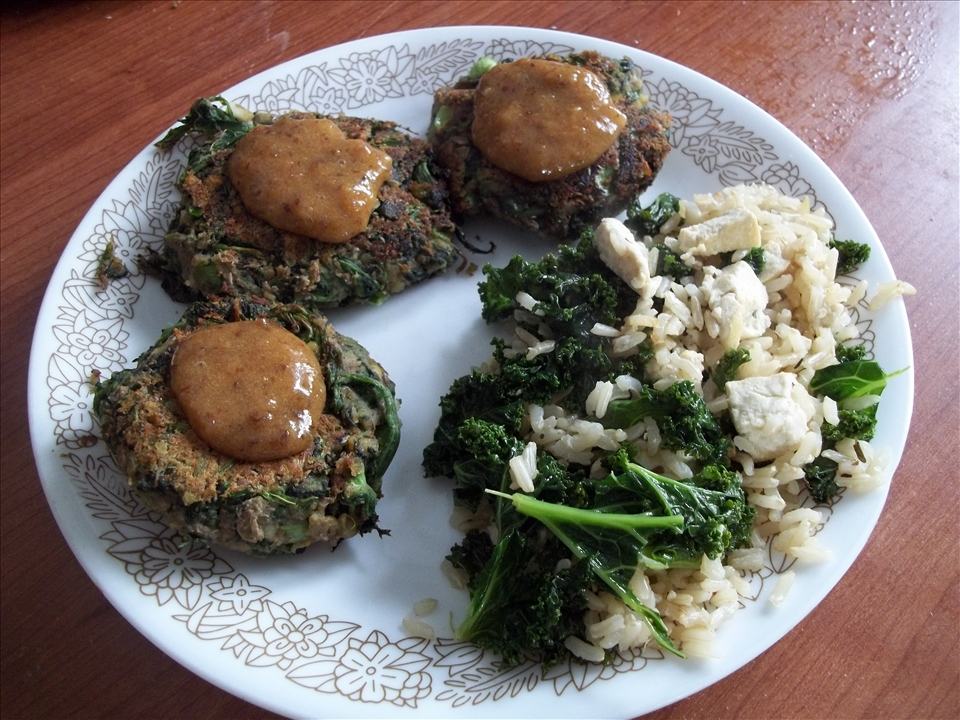 Patties topped with sauce with a side of brown rice with kale and tofu.