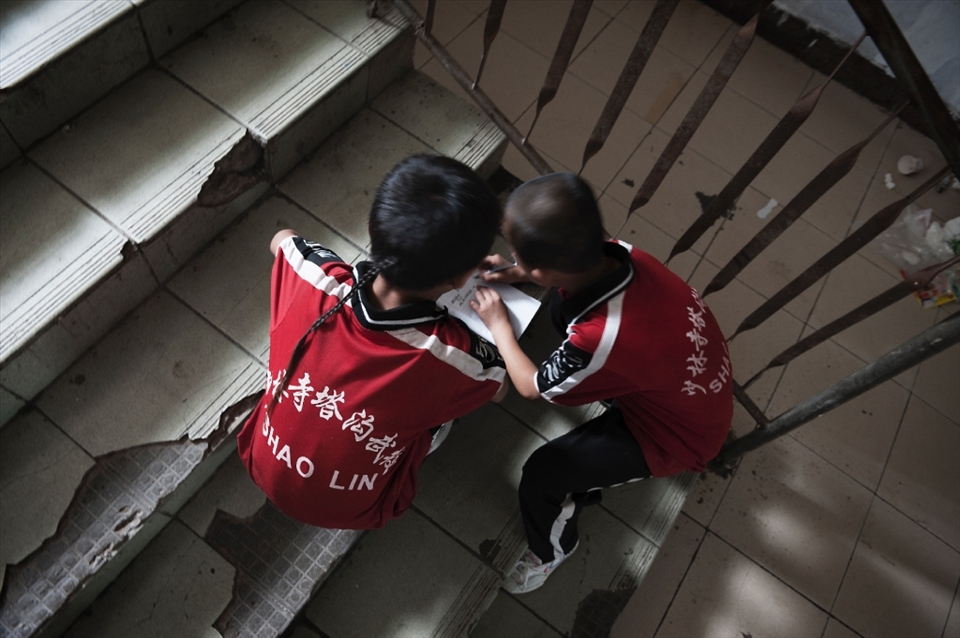 China. Henan province. Dengfeng city. Shaolin Tagou Martial Arts School. Two young students helping each other doing homeworks.