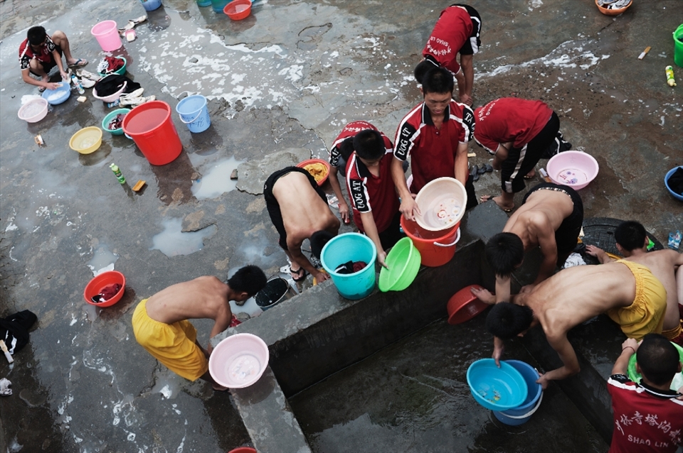 China. Henan province. Dengfeng city. Shaolin Tagou Martial Arts School. Young students washing their tracksuits in the courtyard of the school.