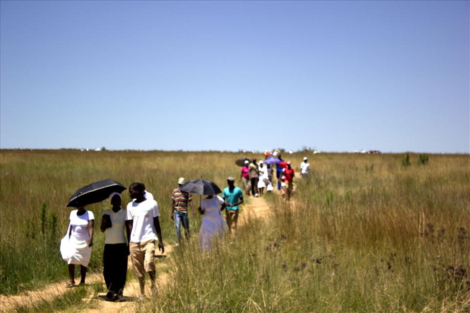 Returning from Church people shield themselves from the harsh sun.