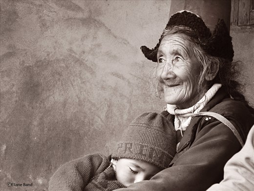 The grandmother was holding the grandson while watching a lama dance 