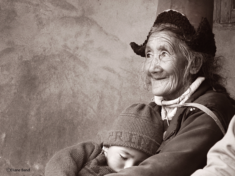 The grandmother was holding the grandson while watching a lama dance 