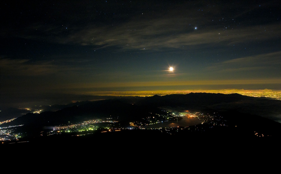 Japanese people start the climb at nightfall to reach the summit for sunrise.  Here, you can see the moon rising over the city of Fujiyoshida.