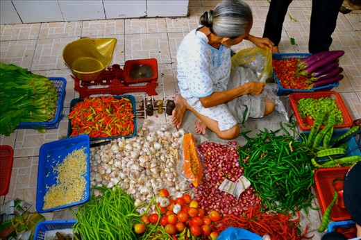 Title: Rich Flavours
Caption:Indonesian food is of the most flavourful I’ve ever experienced, spice being a main component. While this woman sold more than chili peppers, it depicts how vibrant the flavours, and symbolically the colours of each item are. This photo also demonstrates a different physical set up for selling her goods. While many of the vendors were on chairs and had small tables, this woman chose to sit on the floor, and operating her business from lower down.  