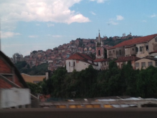 A mansion is silhouetted by a mountainside of ghettos.