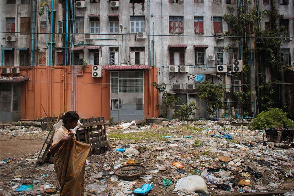 A woman adjusts her longyi as she walks the squalid streets of Yangon.