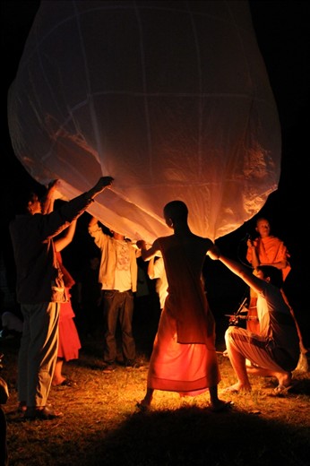 A group of local Thai men and monks setting up the large, single lantern to celebrate the Loi Krathong Festival in their village.