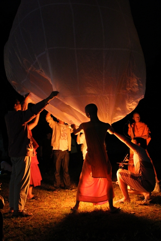 A group of local Thai men and monks setting up the large, single lantern to celebrate the Loi Krathong Festival in their village.