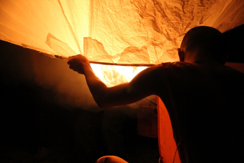 The Northern Thai village's main monk gets ready to let go of the main lantern in their Loi Krathong Festival celebrations. There was a heavy wind this night and it took quite a long time to light the lantern to keep it going.