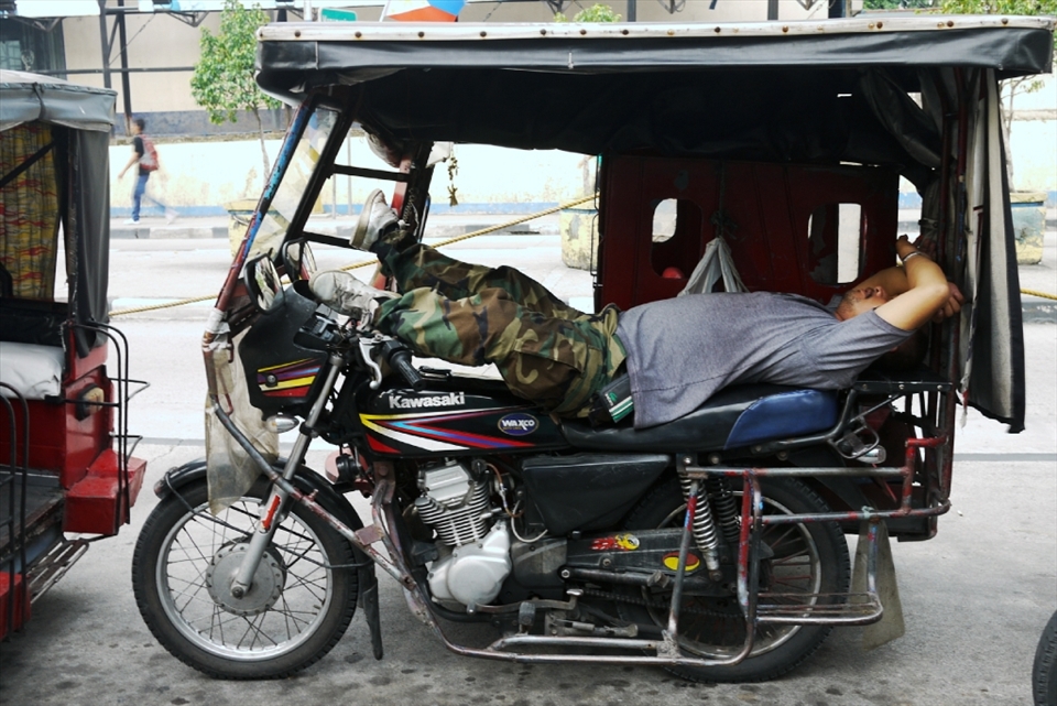 Heir to the jeepney as ¨king of the Philippine road¨ are tricycles, which are quite similar to the tuktuks of Thailand.  Some tricycles, like the one in the picture, could accommodate --- sardine-in-a-can-like --- eight passengers. Here, the driver takes a power nap in his cab, under the blistering heat of the sun --- this is truly a life on the road.