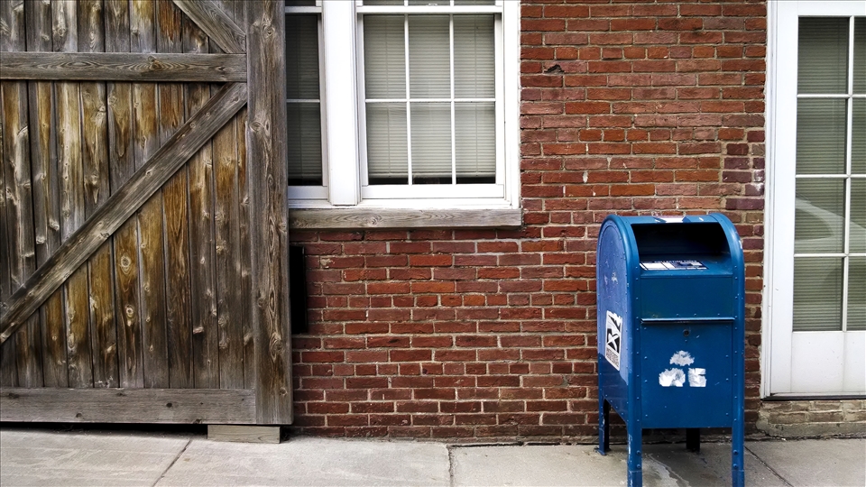Weathered brick, weathered sidewalk, weathered blue box.