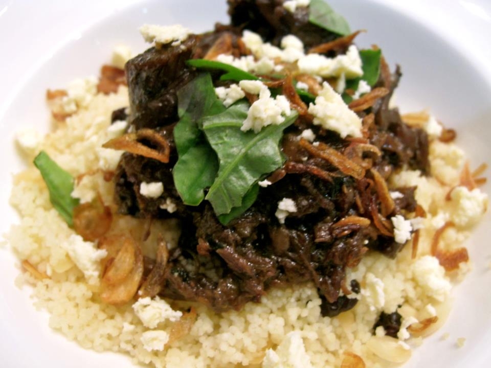 Lamb adobo, plated and served with feta, fried onions and basil over couscous.
