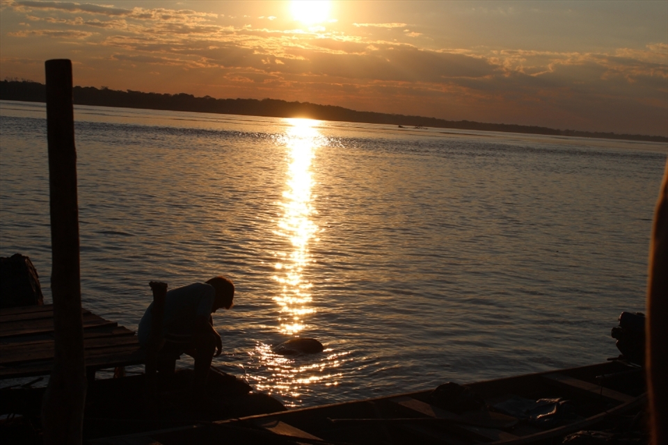 5:20pm. A kid patiently waits at the border of the Amazon river for his ride home while the scorching sun begins its way down...