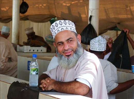 Early in the morning a local is waiting at the famous fishmarket in Muscat, while the fish he just bought is getting disembowelled. He is wearing a kumma, the traditional headgear in Oman.