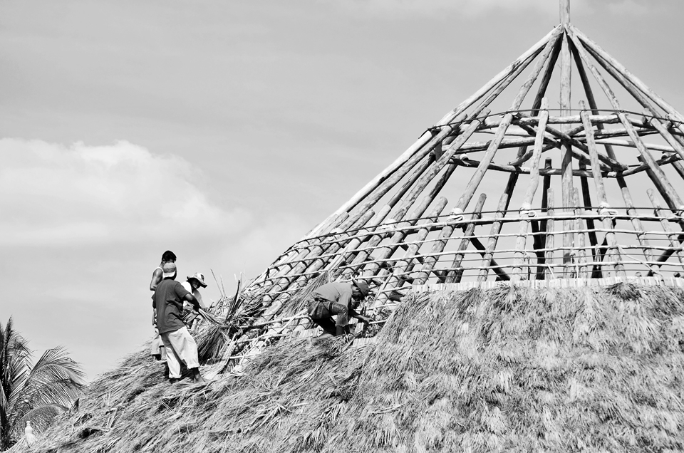 These courageous men work from dawn till late past dusk to erect by hand a roof made from heavy lumber and straw.  These men work from such heights with no safety harness or life lines, However they get to enjoy work under clear blue skies. 