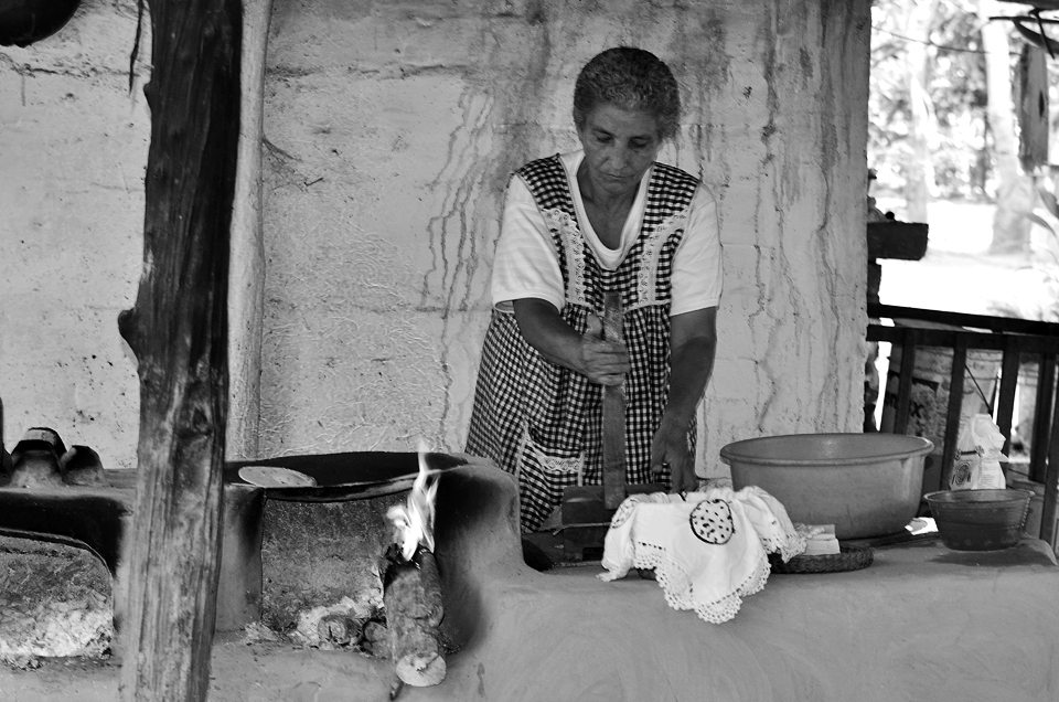 In rural parts deep in the jungle of Bucerias, Maria prepares a home made soft taco for weary adventurers passing by.  The corn is soaked for 3 days before grinding to a dough with a stone mill.  She presses the dough with a home made press and lays the dough on an out door iron plate stove made of stone. She has guacamole, salsa and beans prepped for the tacos.  Delicious.  