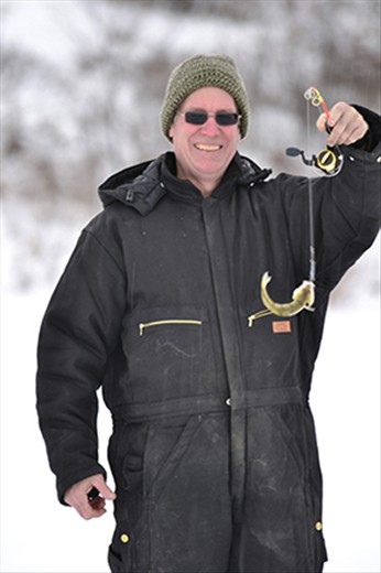 Ron smiles and proudly holds up an immature Walleye writhing in distress. 