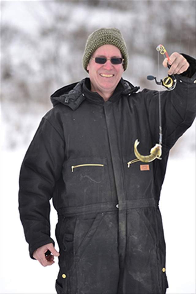 Ron smiles and proudly holds up an immature Walleye writhing in distress. 