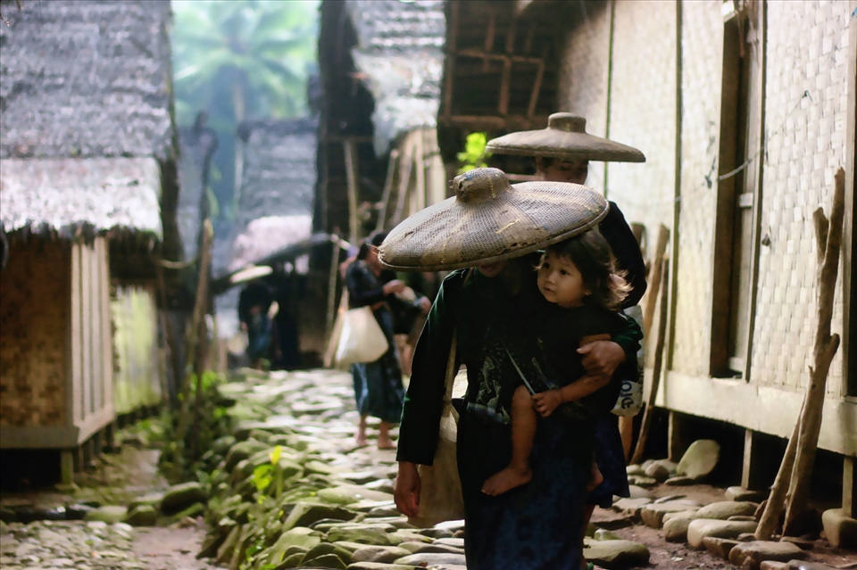 The women with traditional cap carrying her baby leaving her home to the field