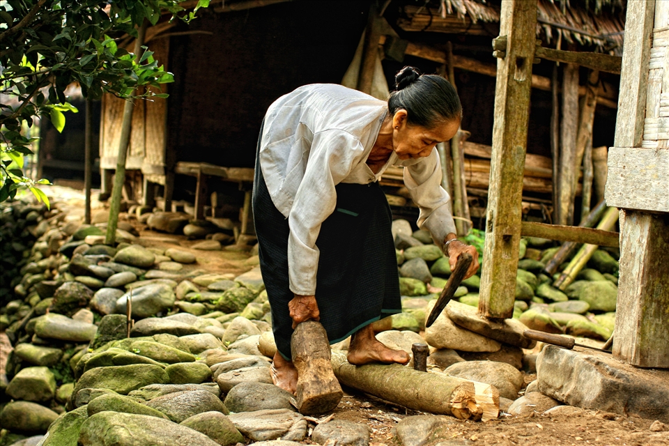 The old woman break the wood with traditional tool to burning the fire for cook