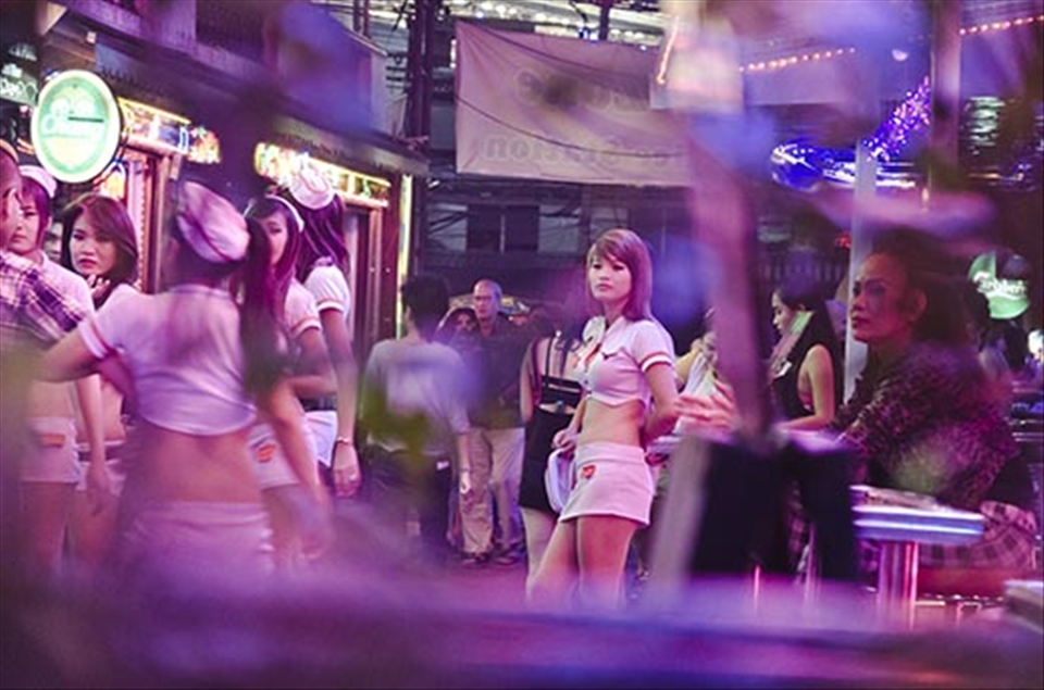 A go go girl stares into distance as her colleagues try and lure tourists in.