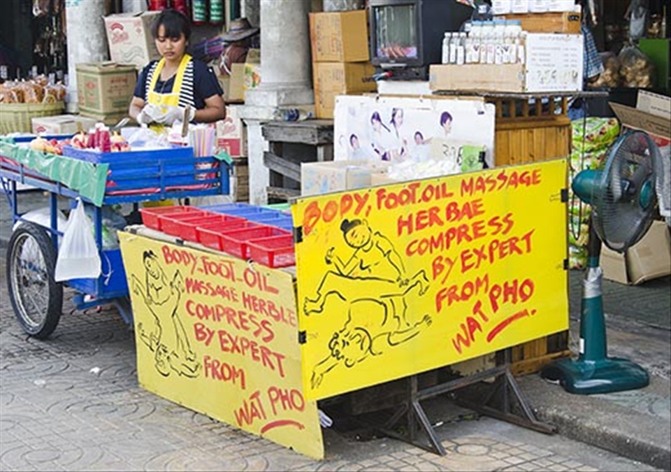A woman seems oblivious of the hilarious sign displayed along her cart.