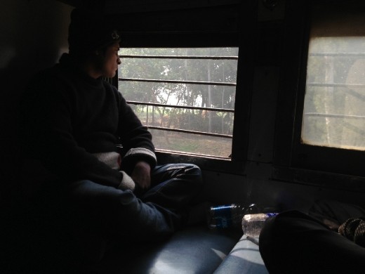 Indiano observando a paisagem pela janela do trem.