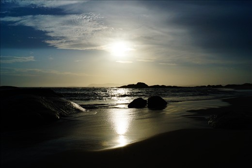 Wet sand shimmers the reflecting afternoon sun's rays