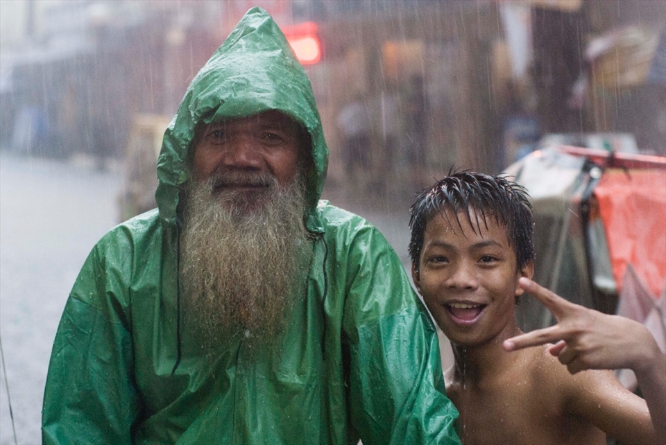 Old man with child smiling in the rain