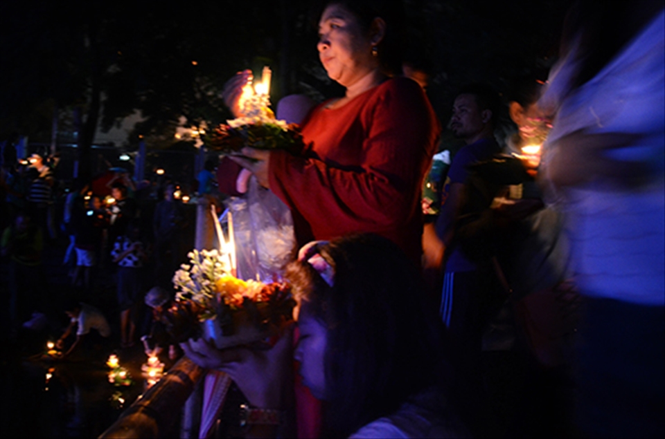 Two women take a silent, reflective moment before releasing their 'krathongs' onto the Ping River. It is said that Loi Krathong originated as a ritual to pay respect to the water goddess. In modern times, the practice has evolved to making wishes before releasing the 'krathongs' and letting one's ill-will and negative feelings float away with the basket.