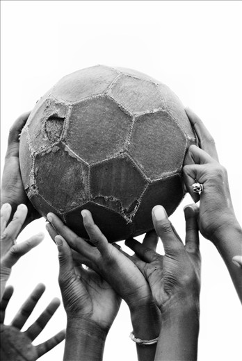 Hold what is important up high. A bunch of children hold up their tattered ball.