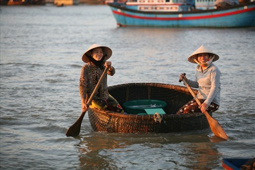 Two happy women coming to shore in traditional wicker Bumboat.