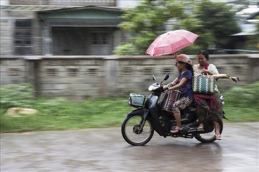 The rainy season is known for its heavy downpours, but not enough to perturb these two women from getting to their destination with their groceries.