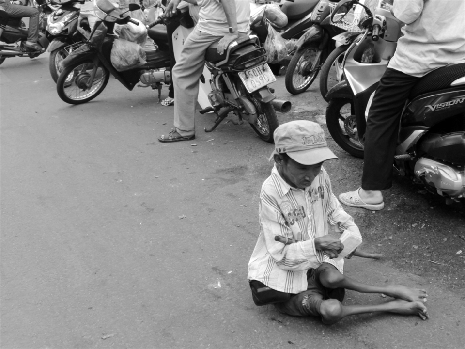 A physically handicapped guy is selling lottery tickets in front of a market