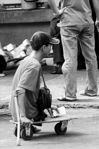 A guy - without legs - is selling lottery tickets in front of a market