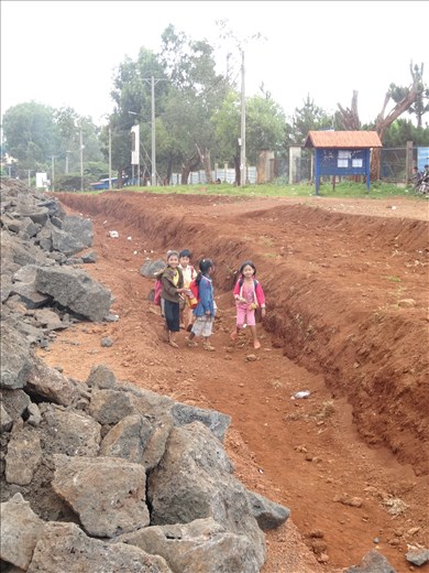 Roadwork continues. Primary school students have to go through ditch to school