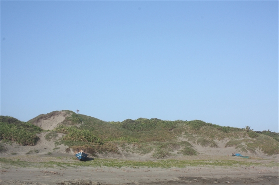 Unused, small fishing boats on the shore. Behind, the Minanga Sand Dunes