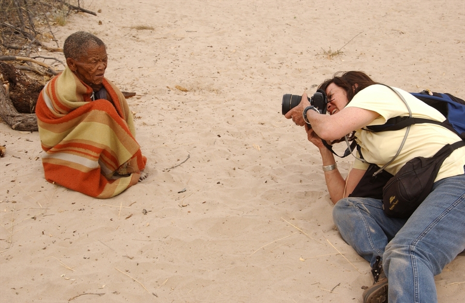 An European photographer taking a picture of an elderly Mosarwa woman (Bushmen) at Central Kalahari Game Reserve in Botswana. This raised questions of is this how the Europeans perceive Africans. 