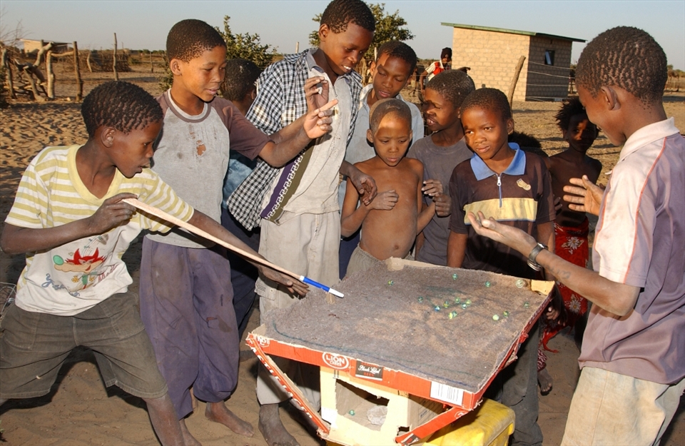 The Bushmen kids dont have recreational facilities or toys. Hence they become innovative. Here they are seen playing a home made game of pool.