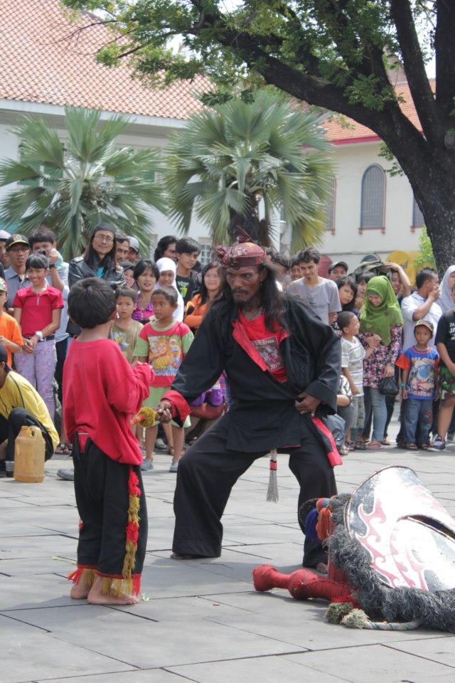 The man shows fake anger to a child in a Kuda Lumping Show