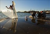 A young fisherman In Cienfuegos, Cuba watches an older man unfurl his net while he cuts bait. Fishermen come to the central pier just before dusk every night to catch the white fish that are then sold to local restaurants and fish mongers.: by grainfedphoto, Views[908]