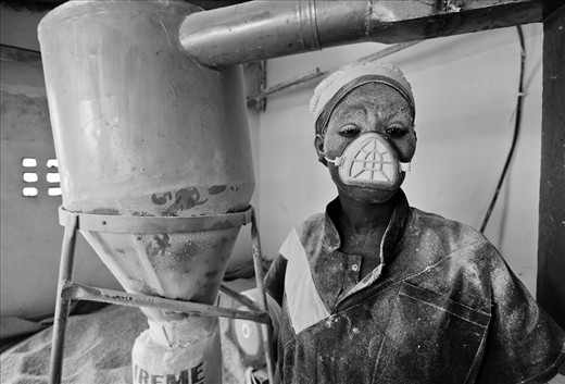 This student had to put the freshly produced maïze flour in bags. 
A lot of flour escapes during this process.
There was only one mouth mask at that time, so she got to use it. 
