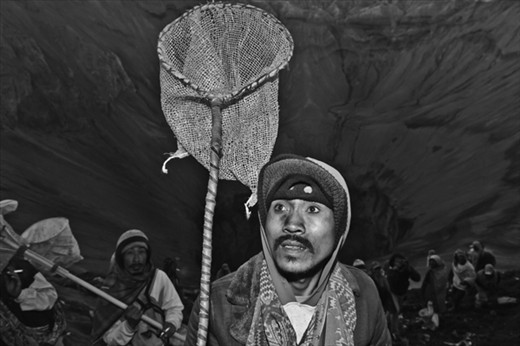 A Tenggerese is waiting for the offering thrown by the Hindunese to the Crater of Mt.Bromo using the net to ease the catch. East Java, Indonesia.