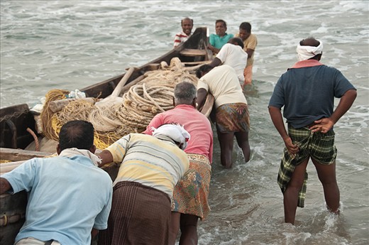 As we getting close to the water begins the most critical step. The weaves are strong and the fishermen cannot stop pushing. They are encouraging themselves all together. When the boat is on a trip they just have to install the long fishing net. 