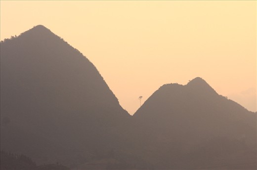 Silhouette of highlands in the sunset (Ha Giang, Vietnam)
Deforested precipices form a surreal skyline in the sunset. Only one single tree adamantly defends its place. 
