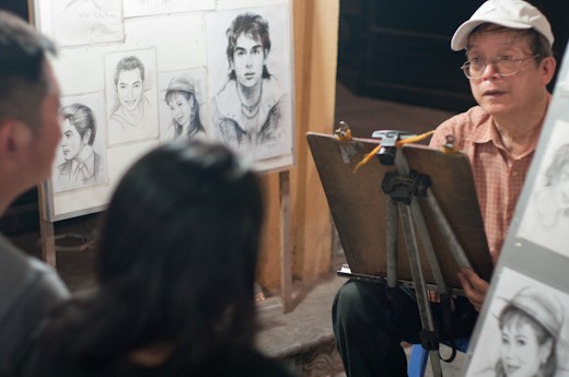 A painter is drawing portraits of a couple.