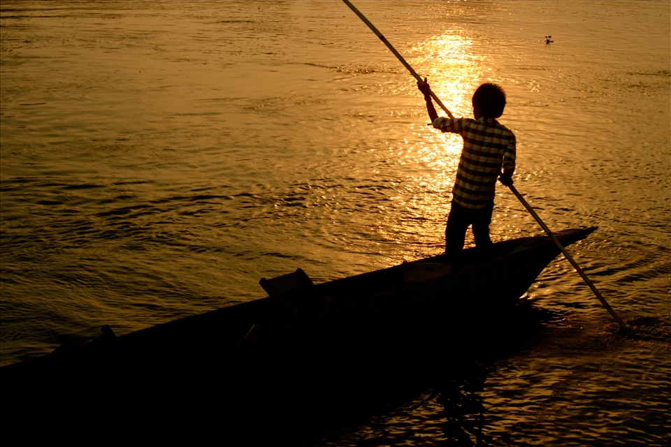 A boy in a dug-out canoe gliding down a river in Chitwan National Park.
