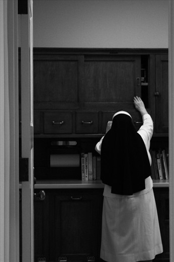 Sister Theresa reaching for a cookbook to make dinner. 