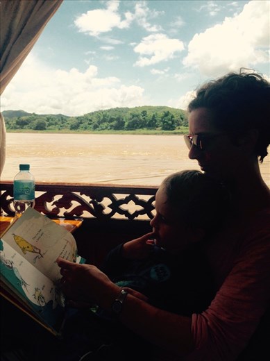 A boat tour on the mighty Mekong river. Reading a book to pass the time during our two-hour trip to the cave.