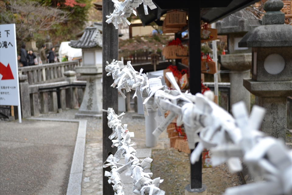 O-mikuji, or ‘sacred lot’ tied to a metal wire line outside Otowasan Kiyomizudera Temple. O-mikujis are small strips of paper with fortunes written on them found at most shrines throughout Japan. Those fortunes that are bad tend to be left behind and tied to the metal wiring. However, some may tie good fortunes as well to increase the effect of their own.